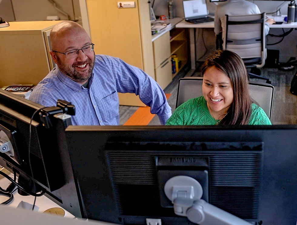 Employees sitting at computer one teaching the other.