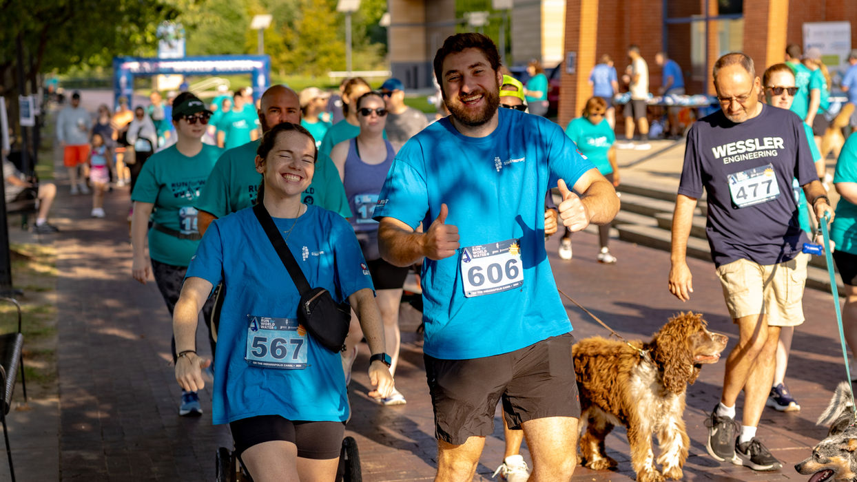 Smiling coworkers at a charity run, highlighting employee benefits and perks.
