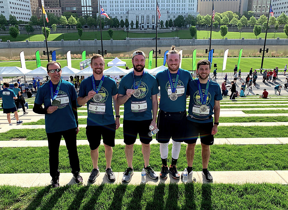 Five team members at a race enjoying employee benefits and perks